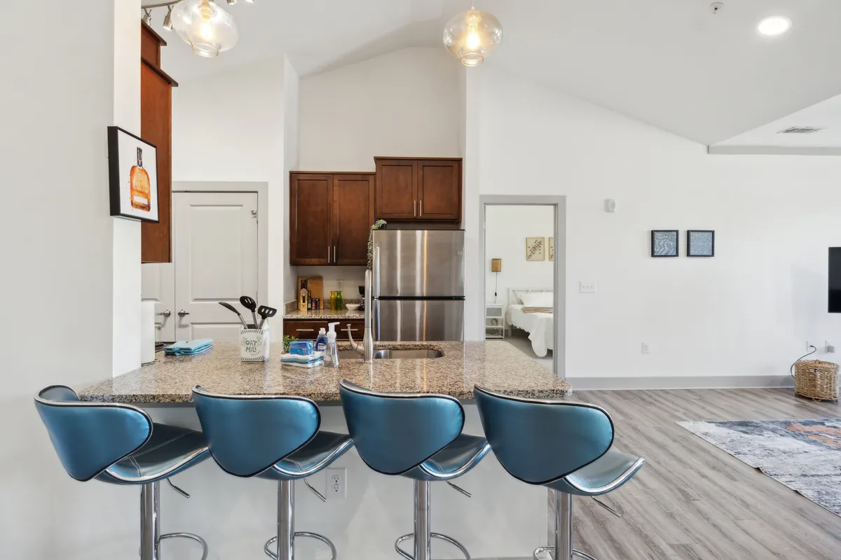 A stylish kitchen area featuring a granite island with bar stools, stainless steel appliances, and tasteful decor. The setting is inviting for casual dining, entertaining, or simply enjoying a morning coffee.